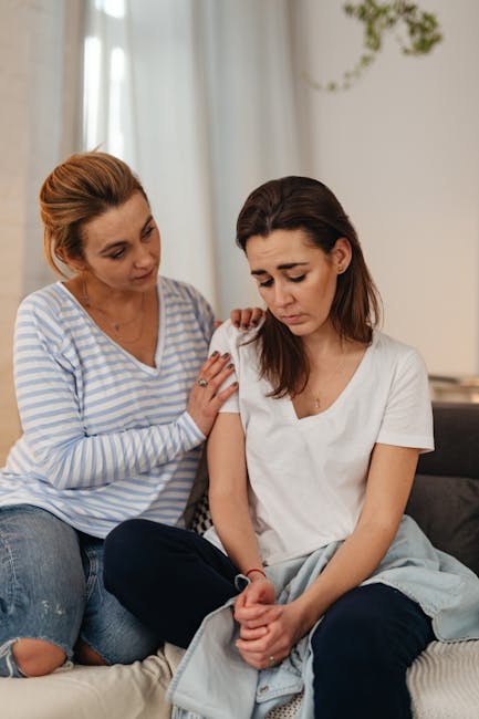 A mother offering support and comfort to her sad daughter indoors.
